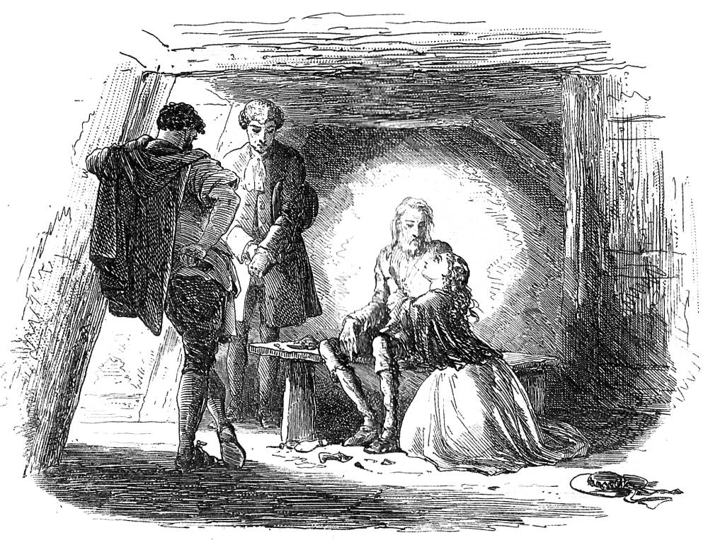 In a confined space, two men stand looking over a third, older man on a bench. A young woman kneels at the older man's feet, looking lovingly up at him.